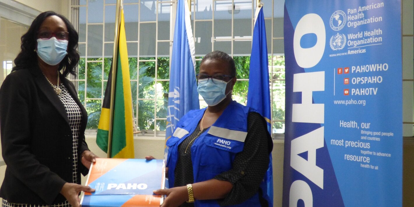 Dr. Michelle Hamilton, Director of the National Public Health Laboratory (left) receives the donation of 6000 Polymerase Chain Reaction (PCR) tests to identify Variants of Concern of COVID-19 (VoC) from Dr. Audrey Morris, Decentralized Regional Advisor, Food and Nutrition (right) at the offices of the Pan American Health Organization/ World Health Organization in Kingston.
