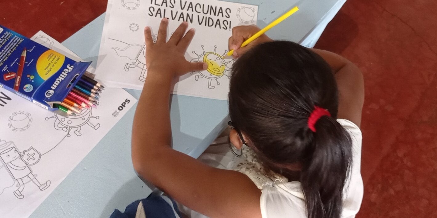 Niña coloreando una hoja con el mensaje "Las vacunas salvan vidas"