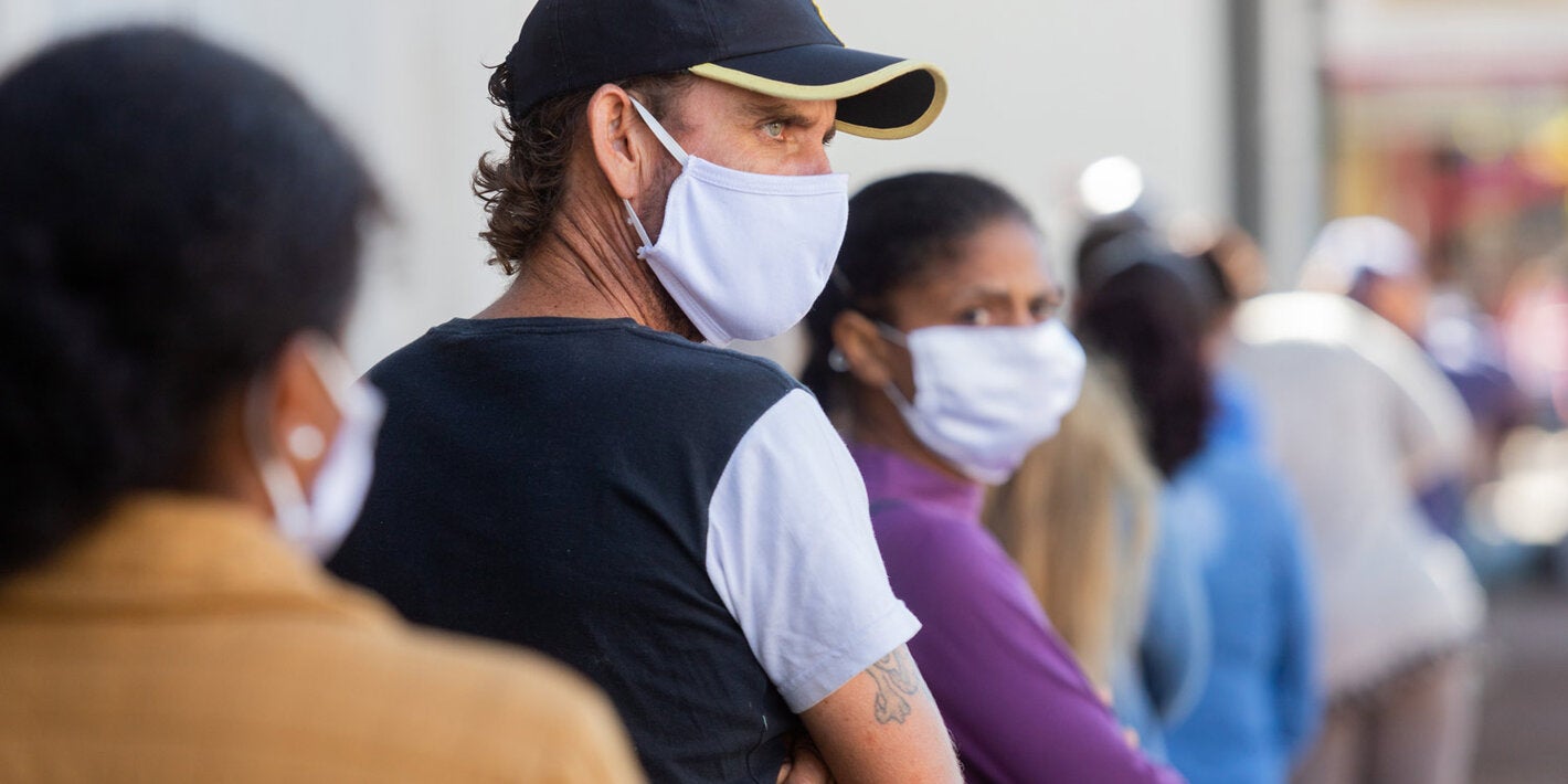 Las personas esperan para entrar a un estblecimiento usando mascarillas.