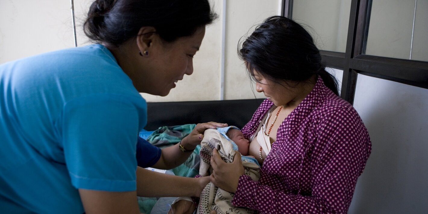 Nurse assisting a mother to breastfeed her baby