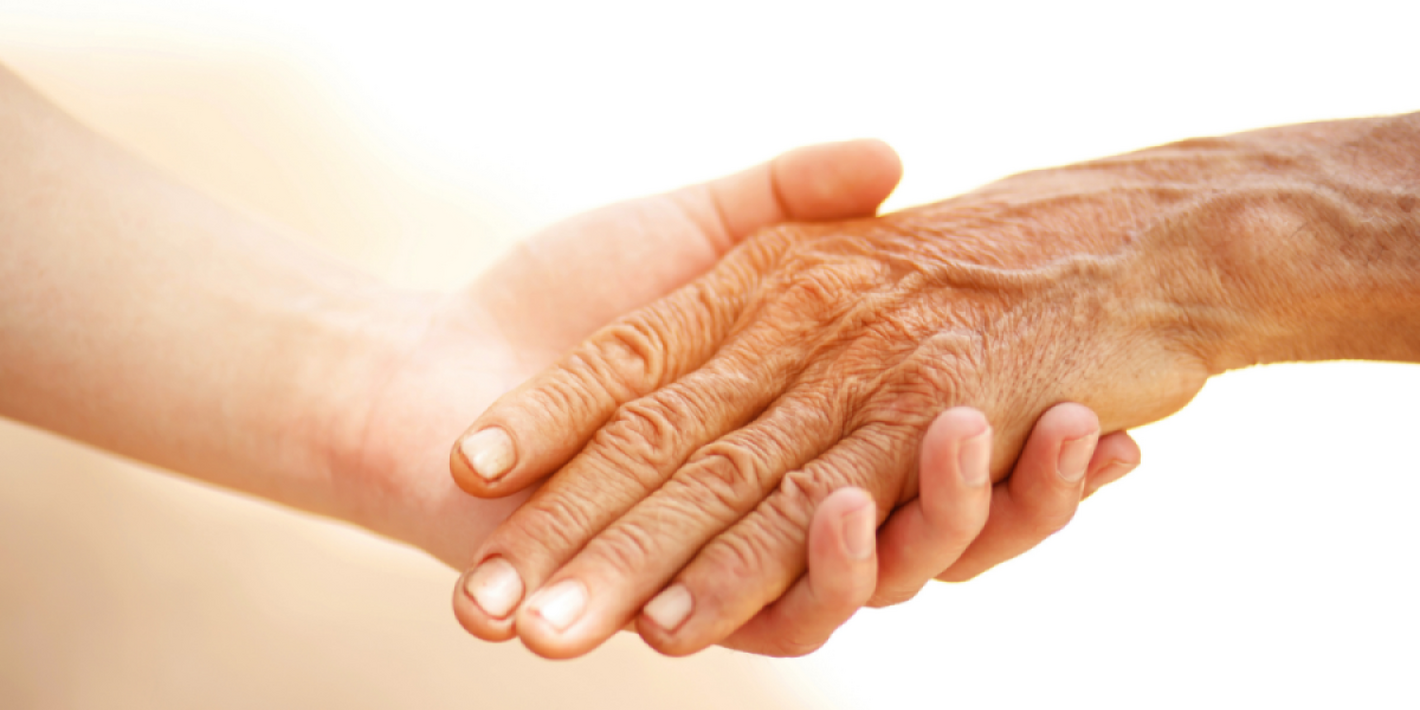 Una mano de persona joven sosteniendo la mano de una persona mayor