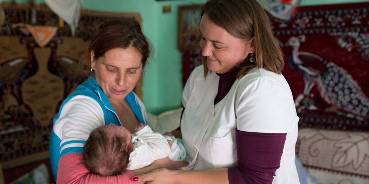 A community nurse examines a newborn baby