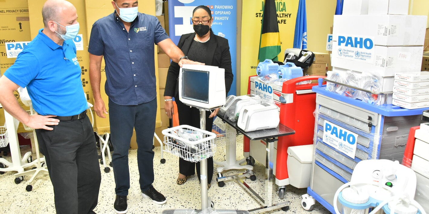 Dr. the Hon. Christopher Tufton, Jamaica's Minister of Health and Wellness (centre) discusses a patient monitor that will be used to assess the needs of a patient’s changing condition. Looking on are (L-R) Mr. Ian Stein, PAHO/WHO Representative to Jamaica, Bermuda and the Cayman Islands and Dr. Marion Bullock DuCasse, Advisor, Health Emergencies