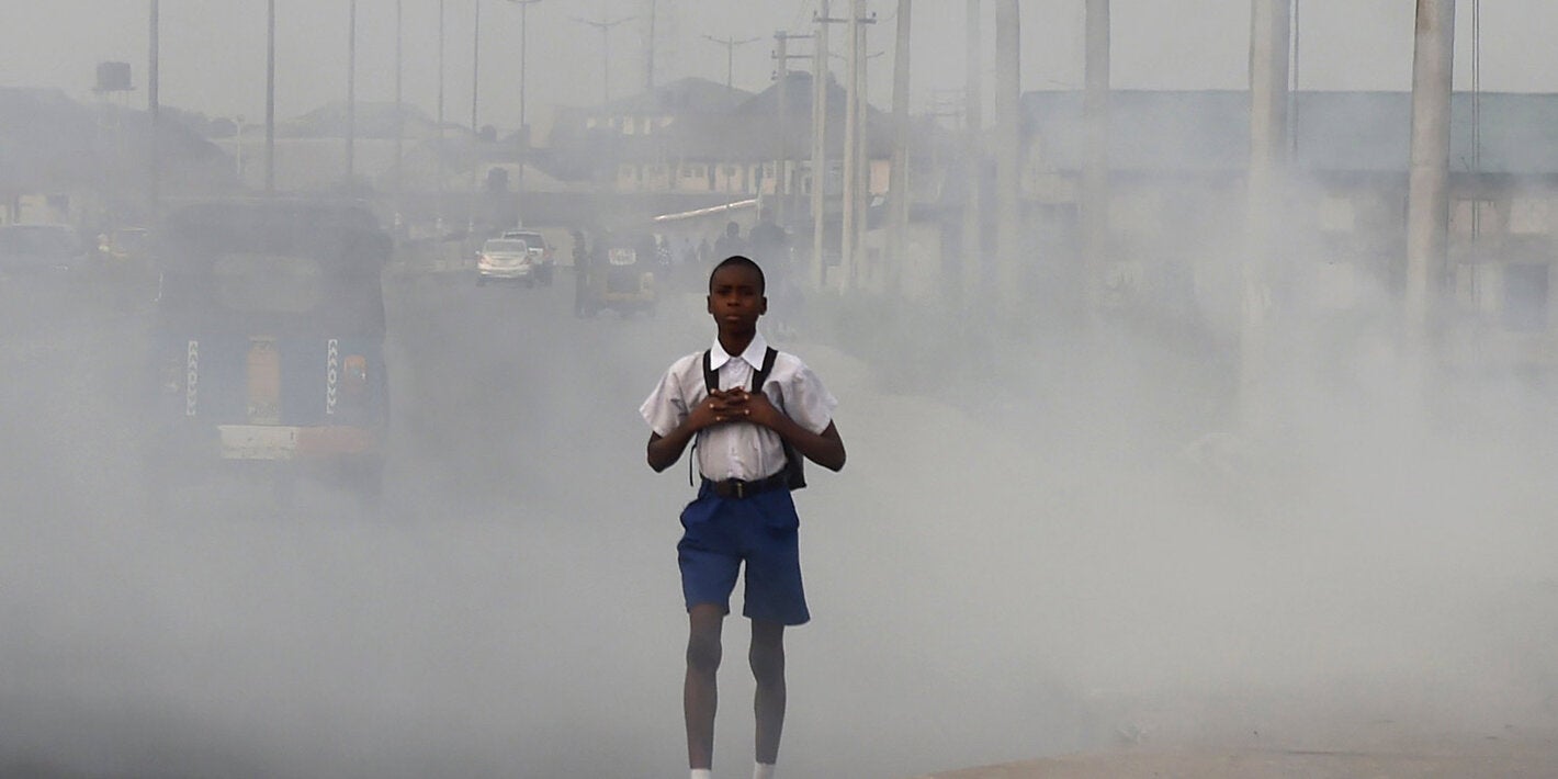 Niño caminando en ciudad con aire contaminado.