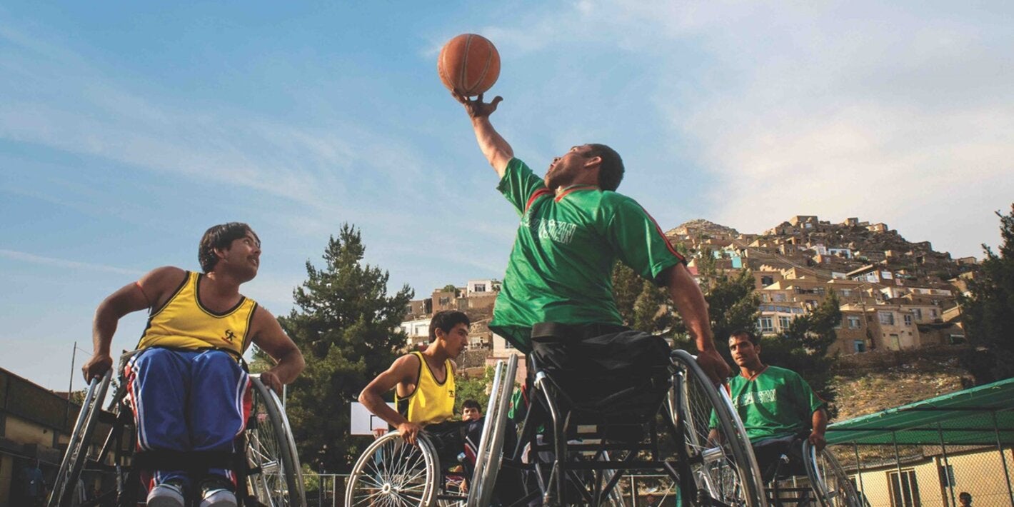 Group of young men playing basketball on wheel chairs