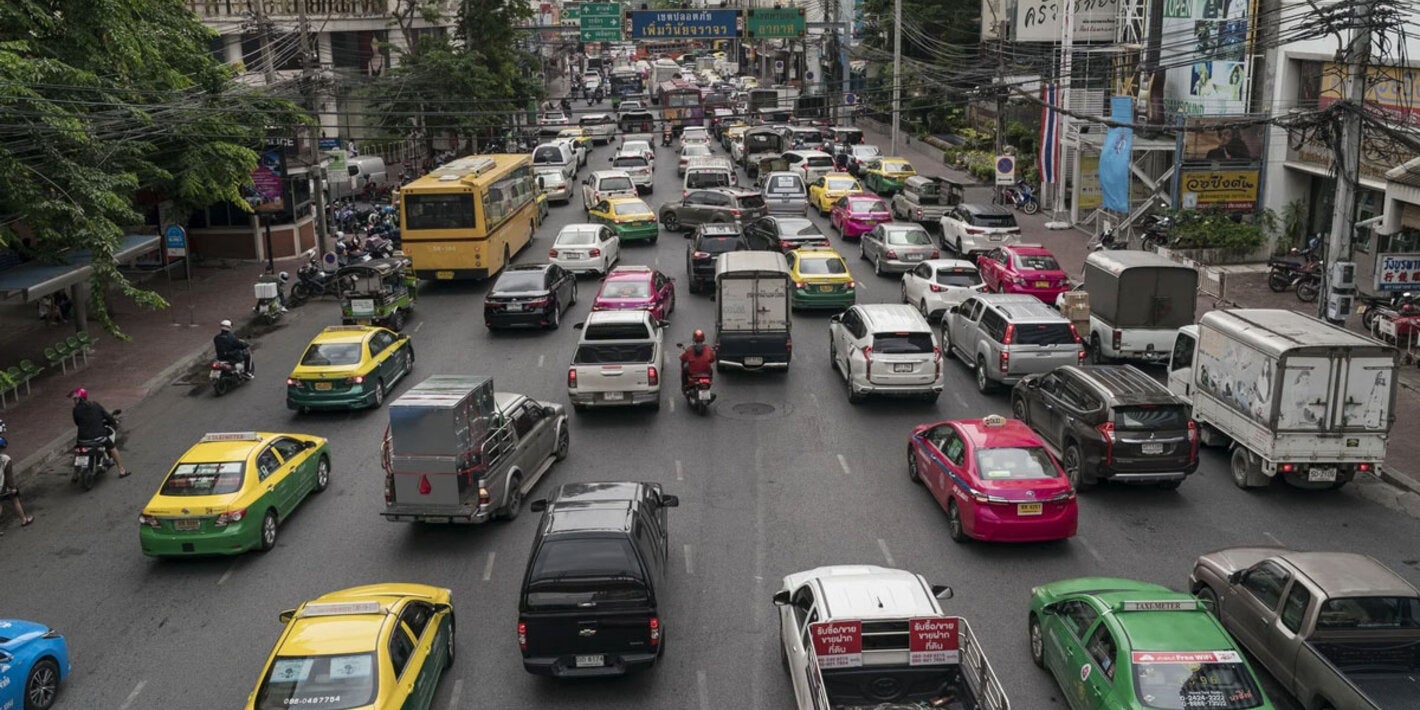 Busy urban street filled with cars and vehicles circulating in the same direction. 