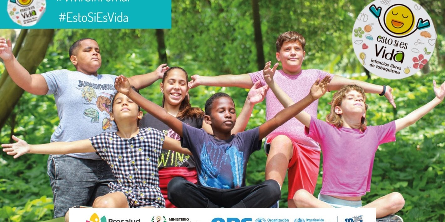 Fotografía de 6 niños con los brazos extendidos y los ojos cerrados, respirando en un entorno natural. Sobre impresos, la identidad de la campaña Esto sí es Vida y los logos de Prosalud, Ministerio de Salud Pública y OPS