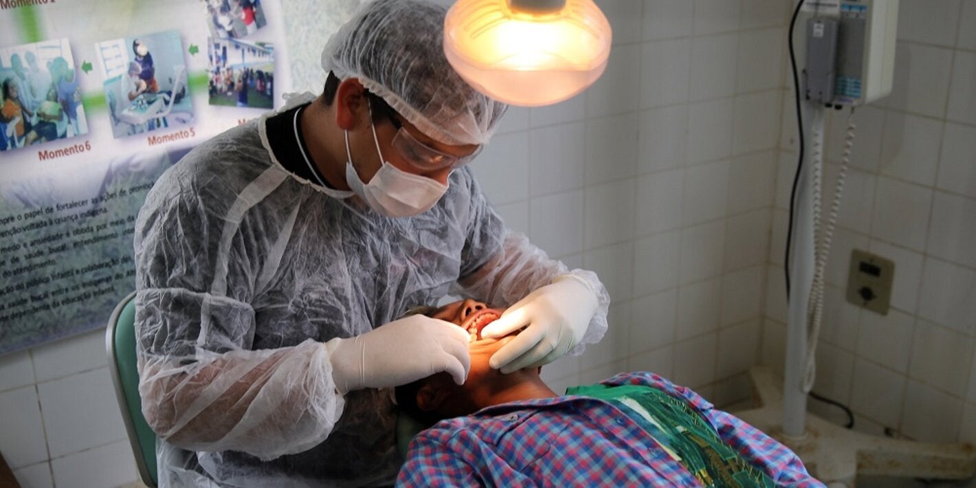 Profissional de saúde realiza procedimento de saúde bucal em homem jovem