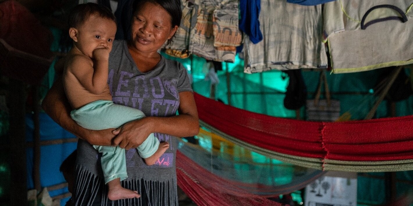 Indigenous woman carrying a toddler on her arms