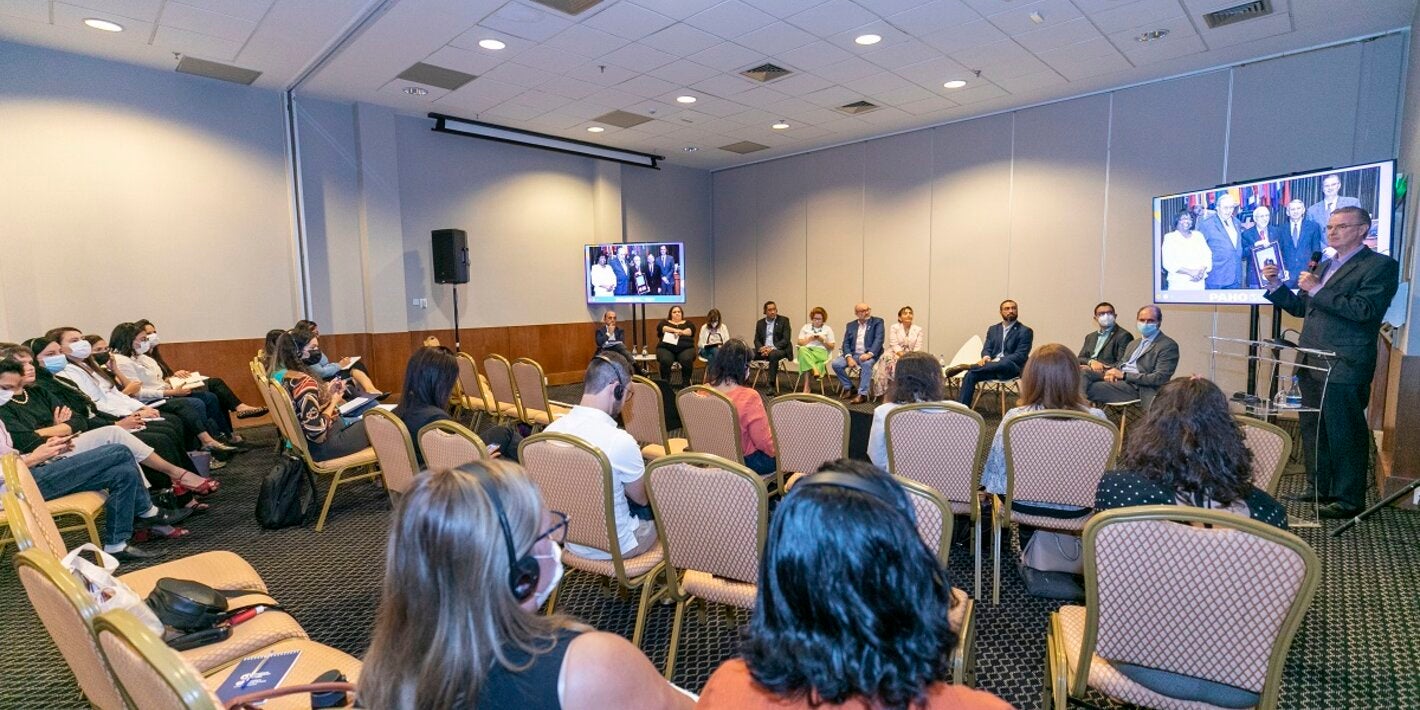 Imagem mostra pessoas em uma sala participando da Reunião Regional de Monitoramento e Reverificação da Eliminação do Sarampo no Brasil