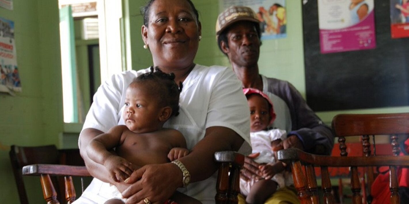 Mujer sentada con bebé y, más atrás, hombre con bebé