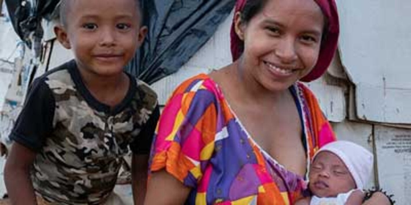 Mujer con niño y bebé, sonriendo a la cámara