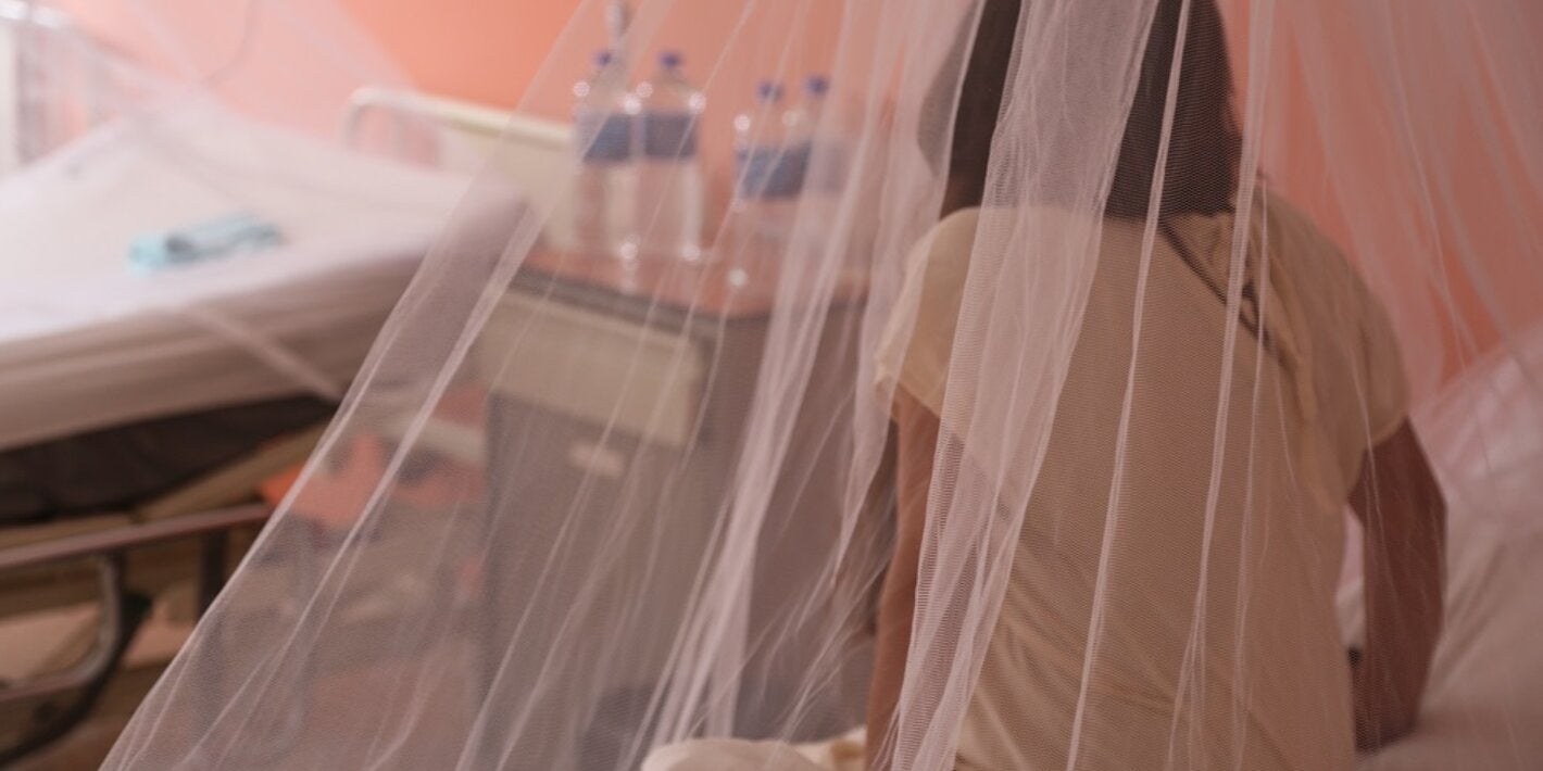 Chica sentada en una cama, de espaldas