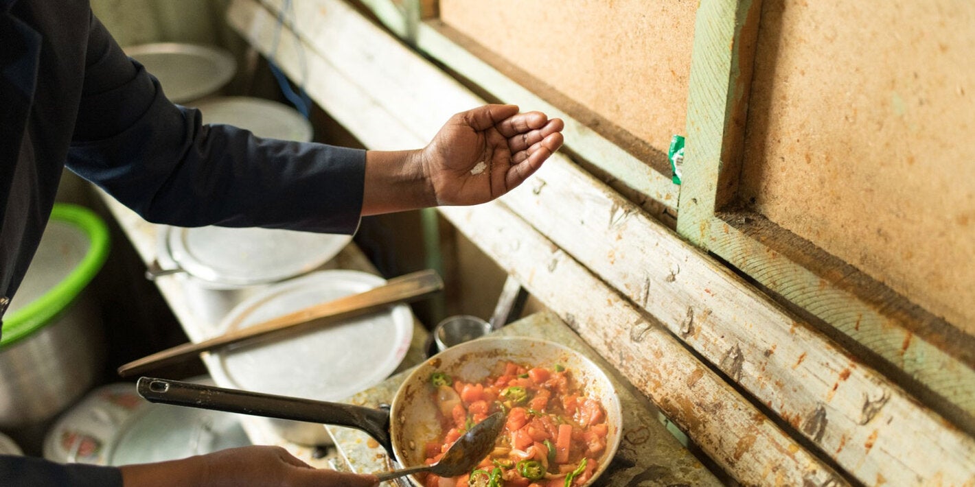 A person is adding salt to food as it cooks