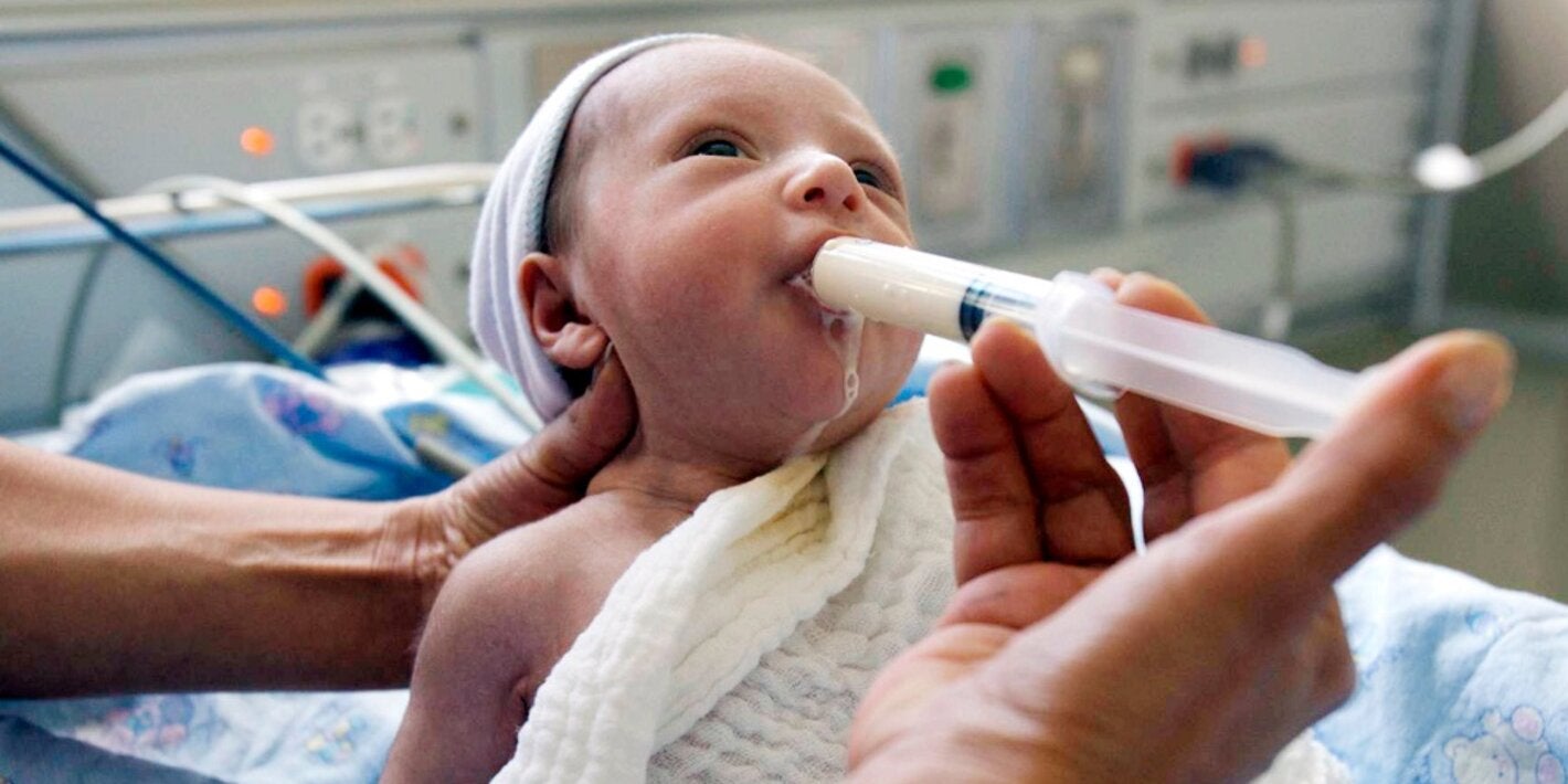 Bebé siendo alimentado de leche humana a través de una jeringa