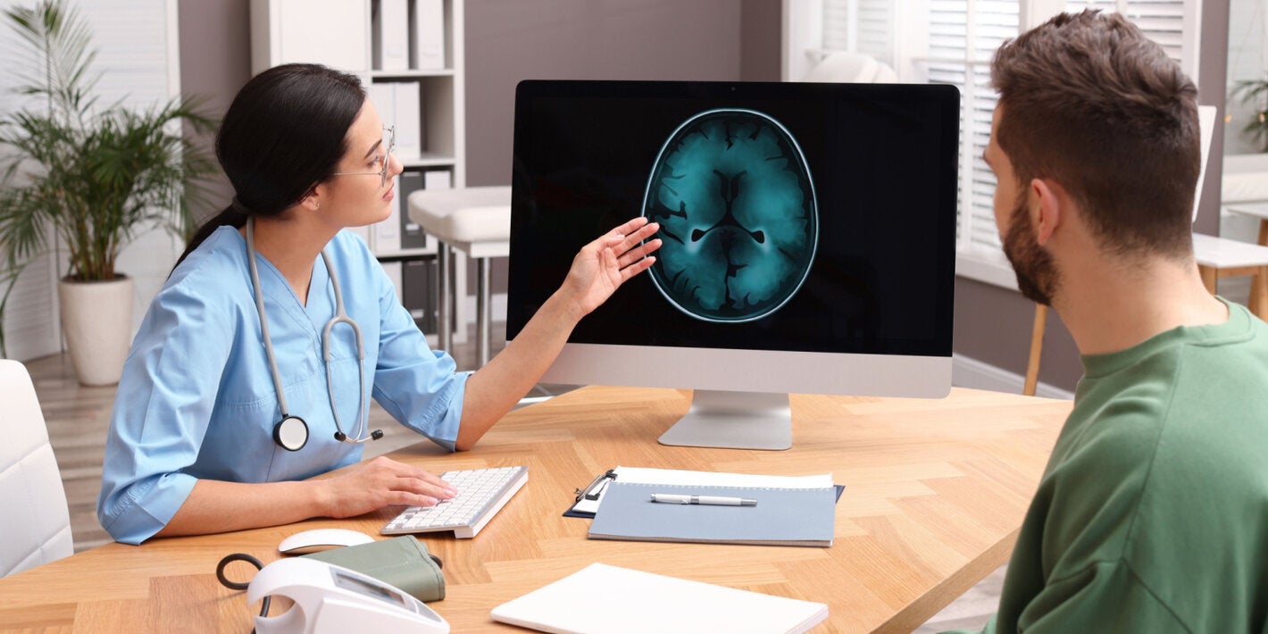 A female health worker shows the image of the brain to a male patient
