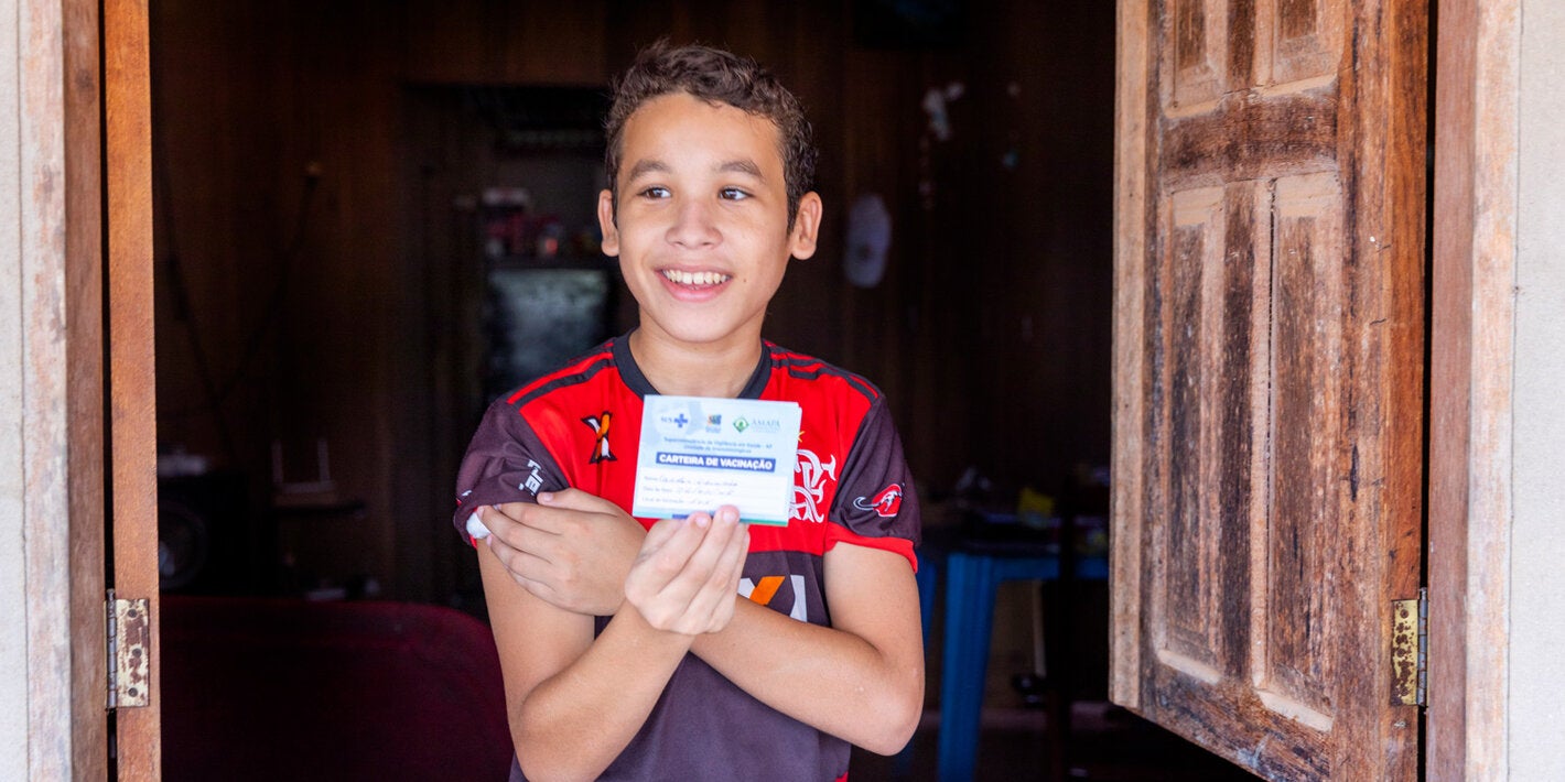 Menino vacinado com a caderneta de vacinação na mão