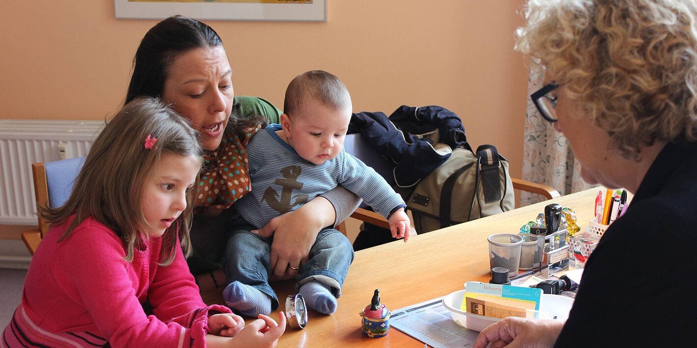 A doctor explaining vaccination procedures to a mother with her two young children.