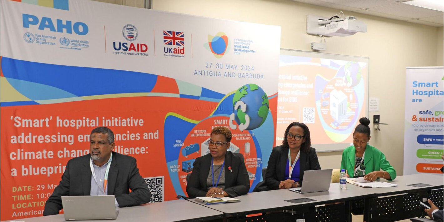 Event panelists seated. Event banner behind them.