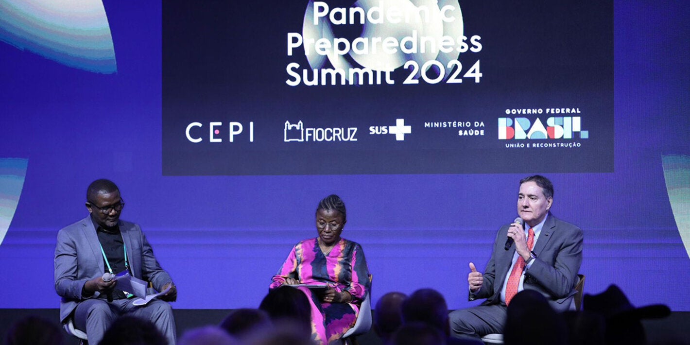 barbossa sits on stage at summit beside two others and speaks