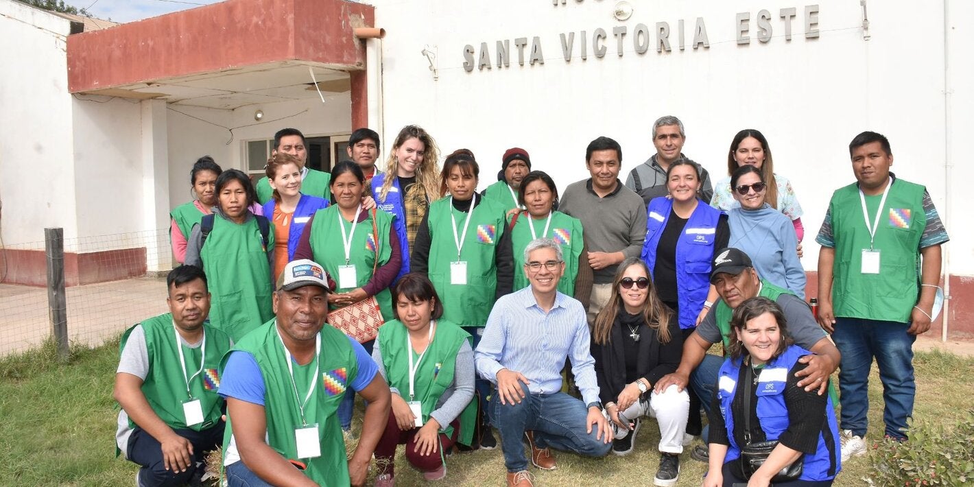 Foto grupal de las personas que participaron de la actividad con el hospital de fondo.