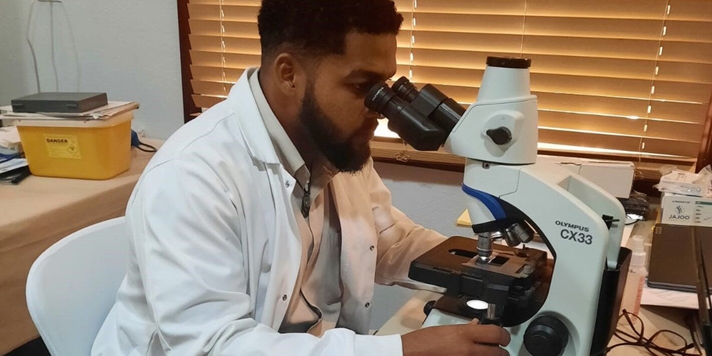 Man in lab looking through the microscope