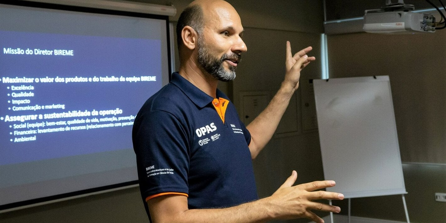 Foto de João Paulo Souza, Director de BIREME, con una camiseta de la OPS, hablando y gesticulando en una ponencia.