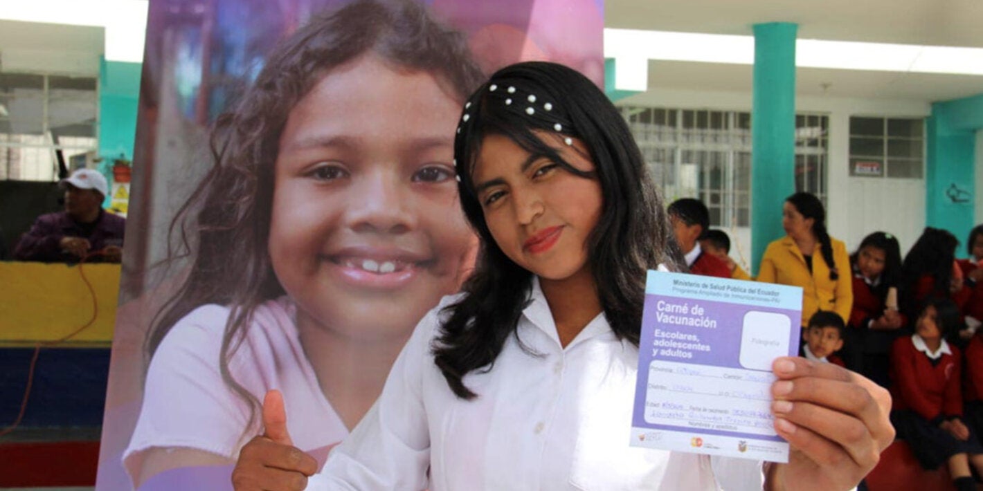 Girl poses with vaccination booklet in hand after receiving vaccine