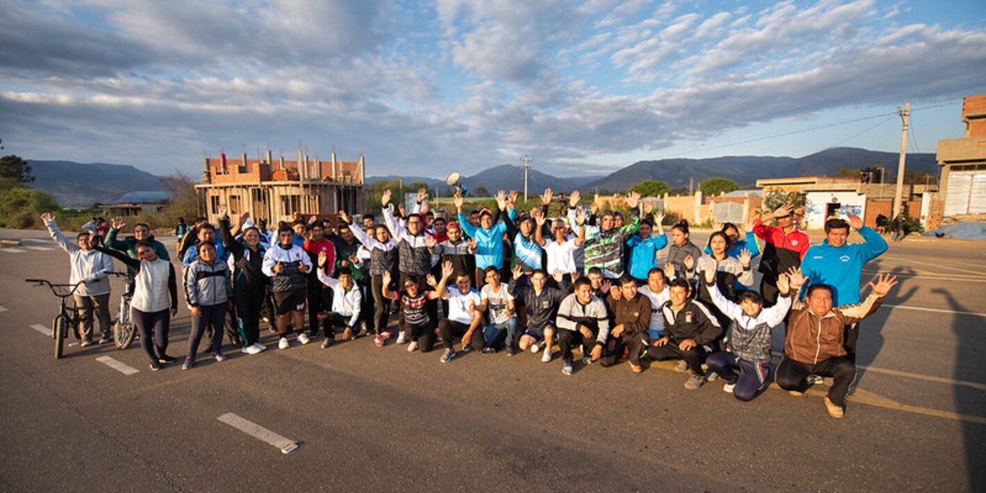 imagen de un grupo de personas con las manos levantadas en señar de victoria, en un paisaje rural.