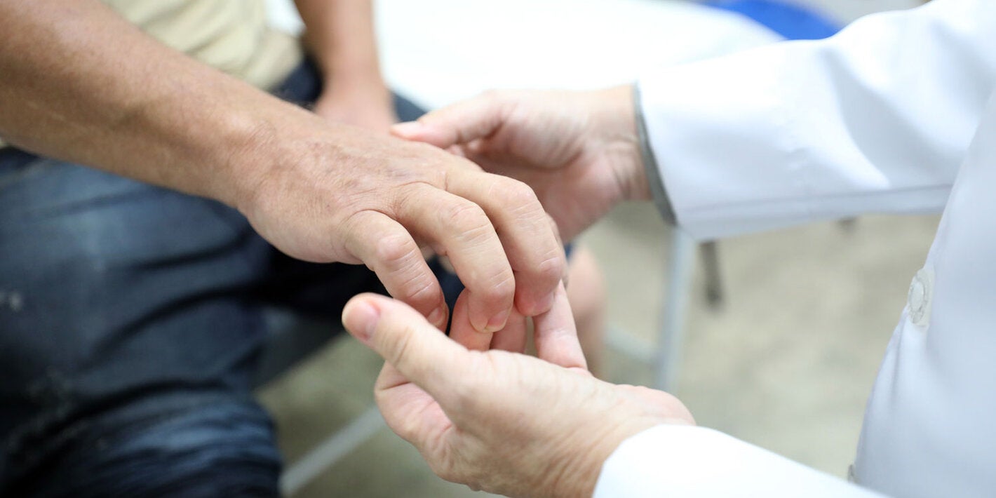 Profissional de saúde examina mãos do paciente