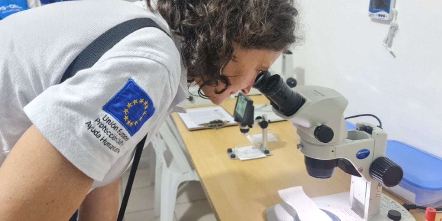 Mujer mirando en microscopio