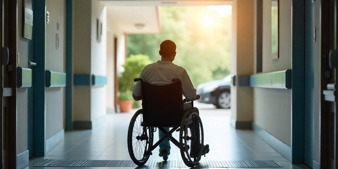 person with disability in a wheelchair, at a hospital entrance