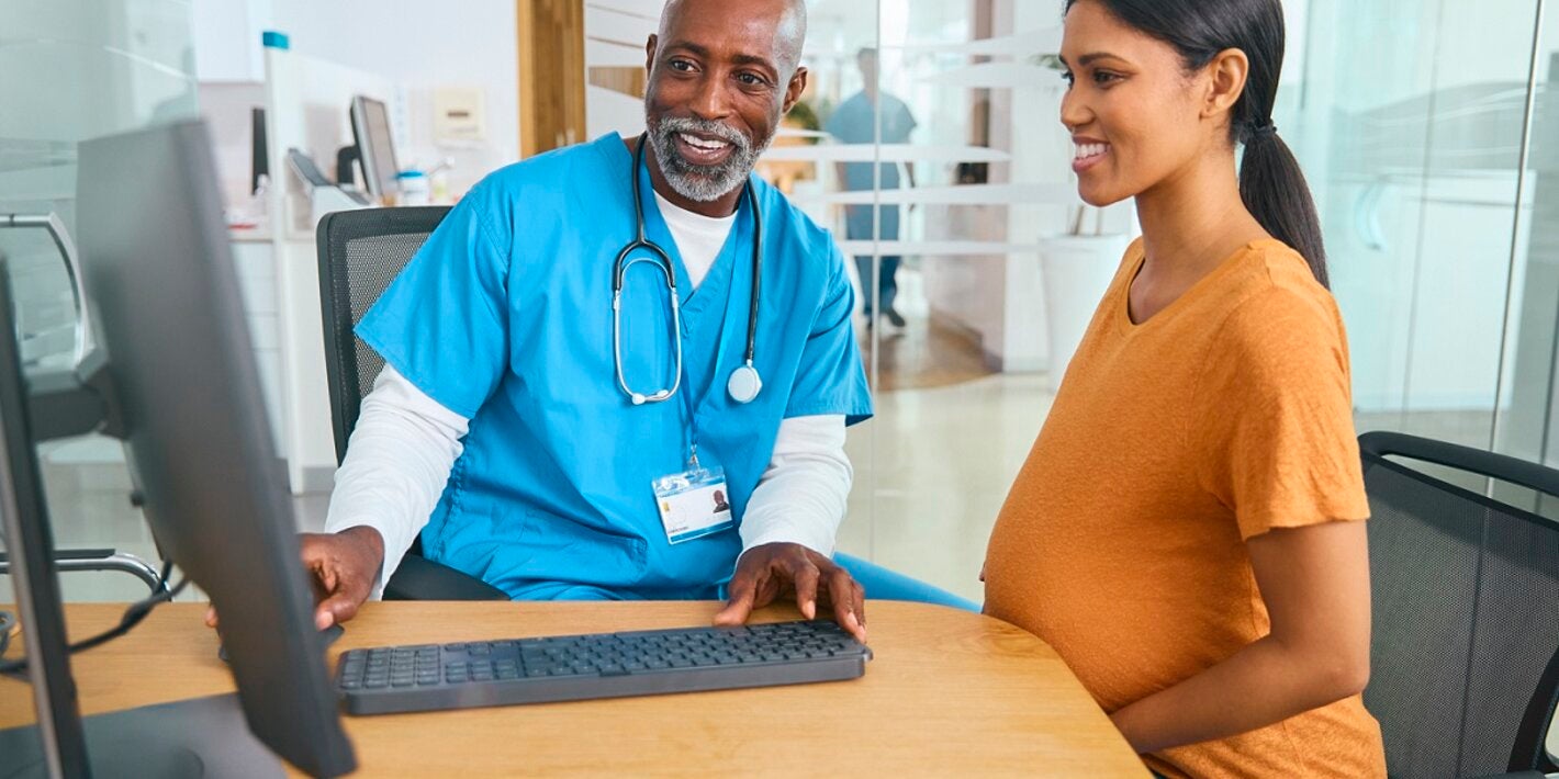 Male doctor and pregnant patient review electronic medical records
