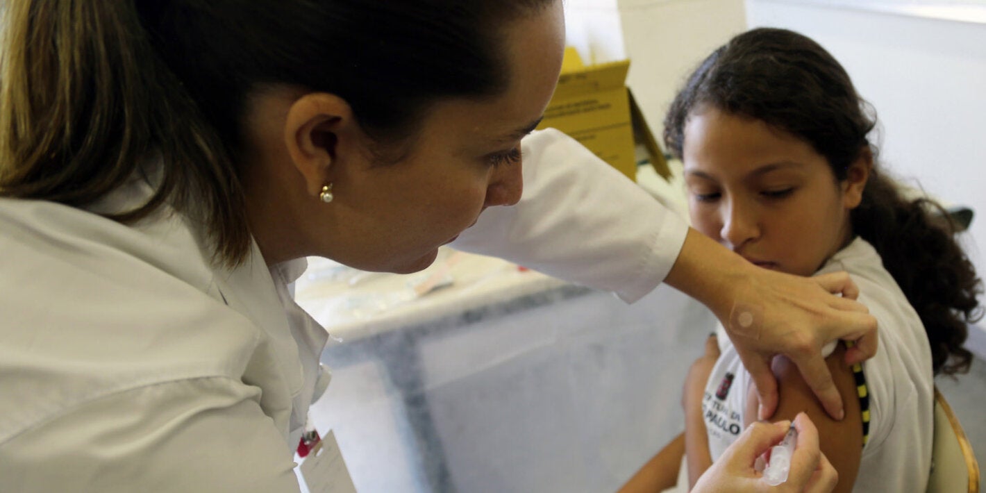 vacunando un niña con uniformer escolar
