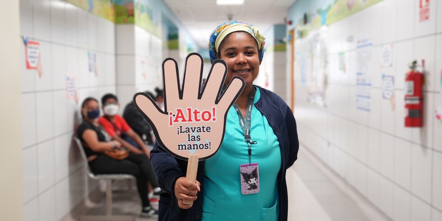 personal de salud sostiene una pancarta alusiva a la higiene de manos