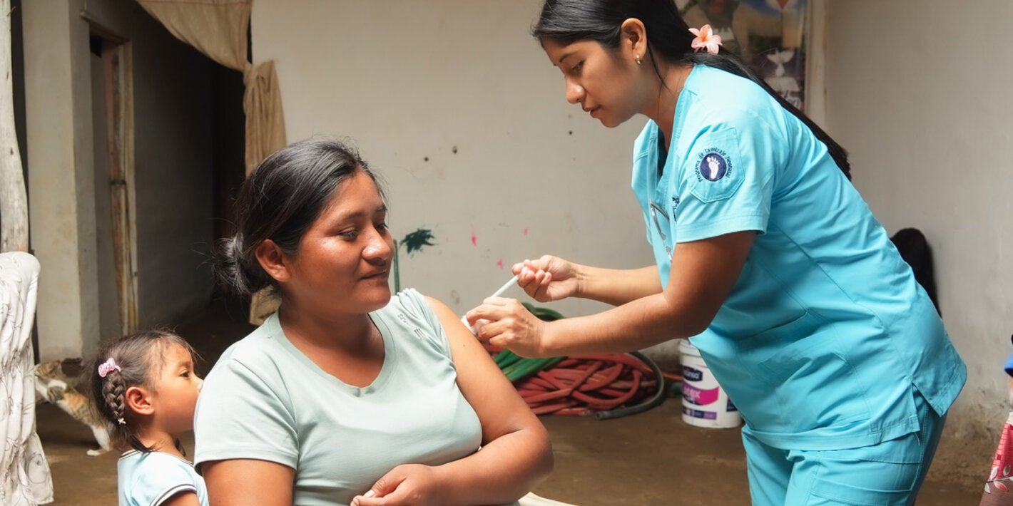 Personal de salud aplica la vacuna a una mujer junto a su hija pequeña