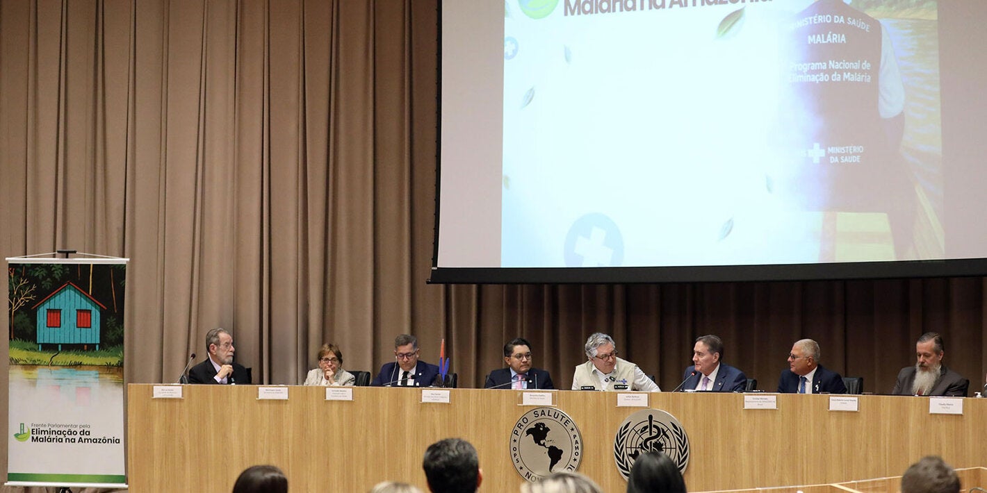 Mesa de abertura do evento com telão ao fundo com a inscrição "Frente Parlamentar pela Eliminação da Malária na Amazônia"