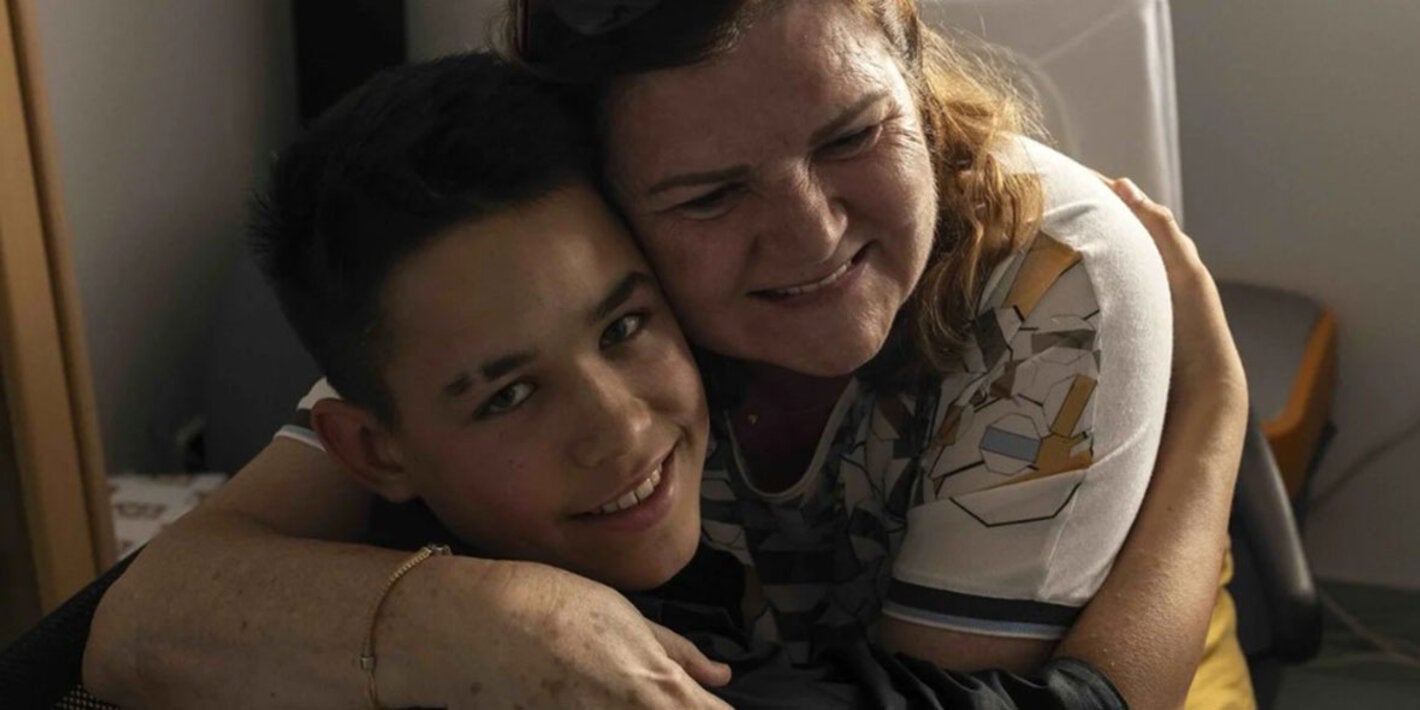 Mãe abraça filho e ambos estão sorrindo 