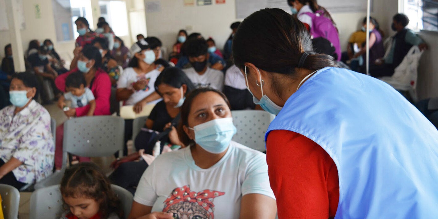 Personal de salud conversa con paciente en una sala de espera 