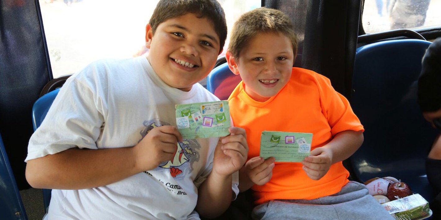 Boys show their vaccination record cards