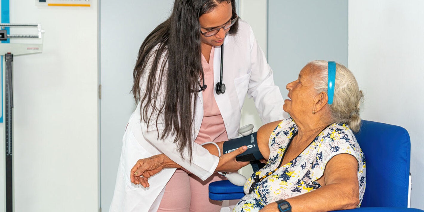 Atenção Primária - Uma mulher idosa tem sua pressão arterial verificada