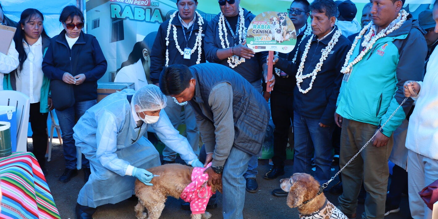 Autoridades y veterinario vacunando un perro contra la rabia en la frontera Bolivia-Perú