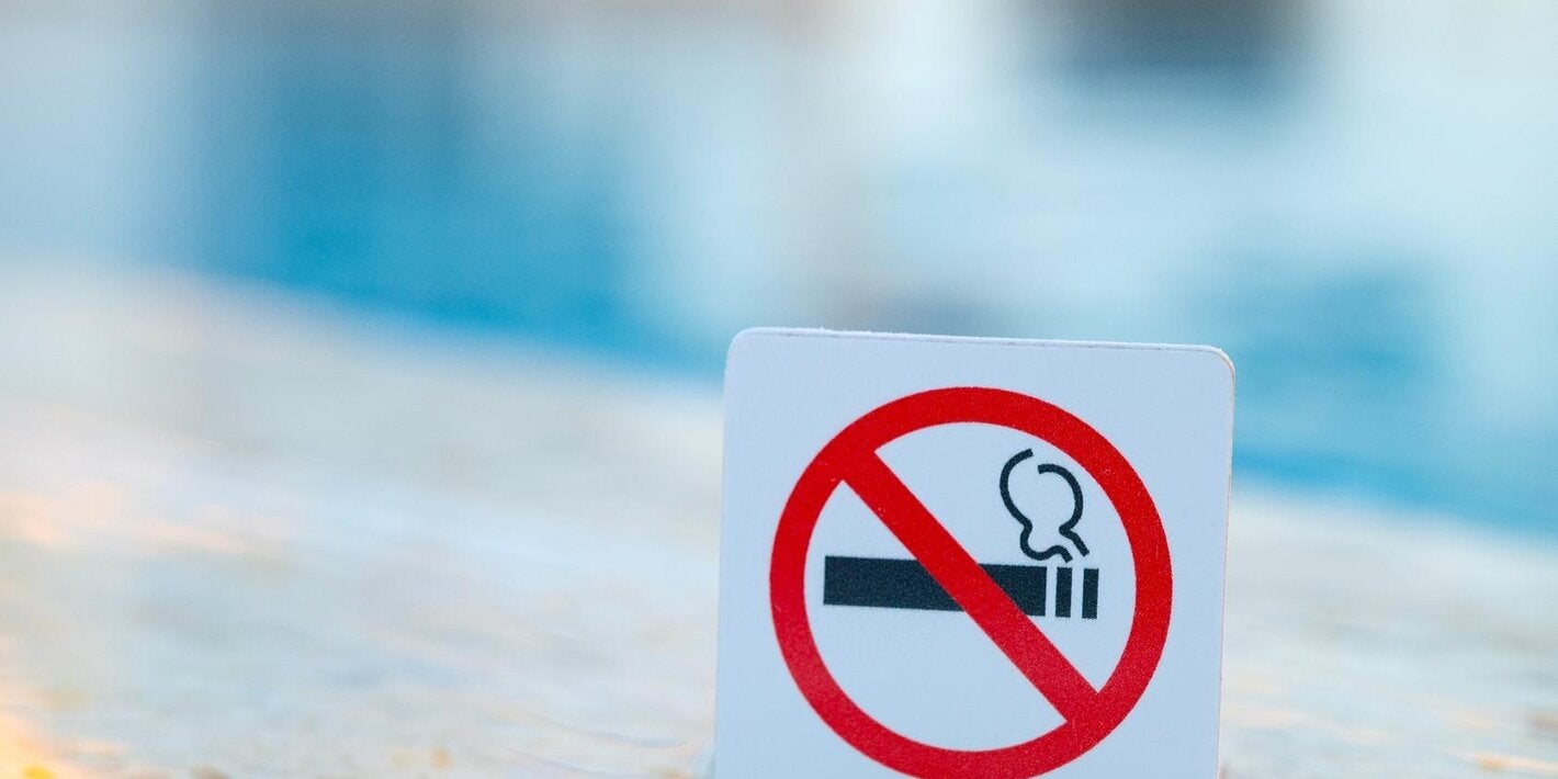 Signo de "no fumar". Está prohibido fumar en lugares públicos. Señal de prohibición cerca de agua azul en la piscina