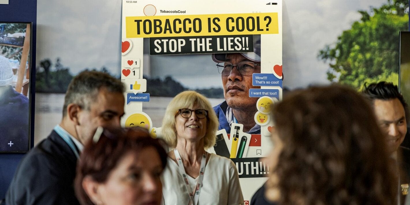 Image of a campaign booth warning about the lies of tobacco products, with some people around it