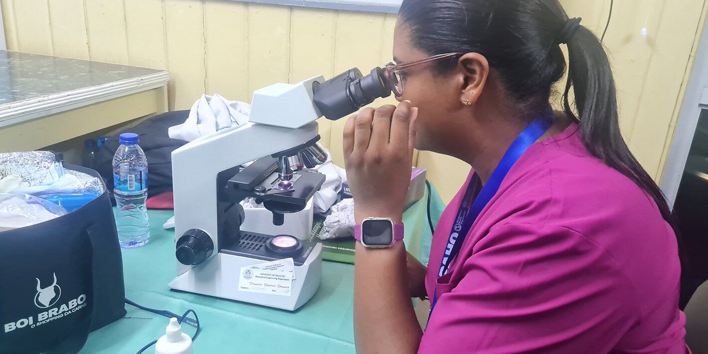 woman looking through microscope
