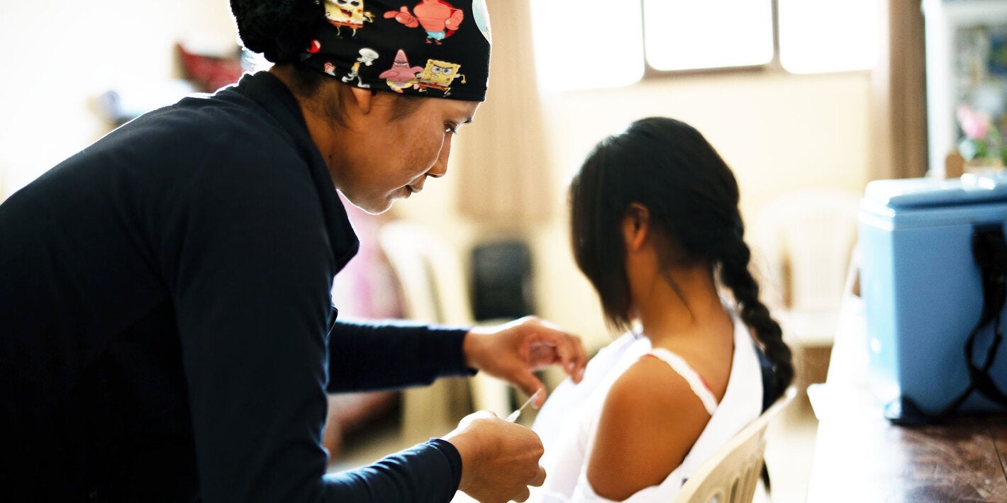 Health care worker applying a vaccine to a girl
