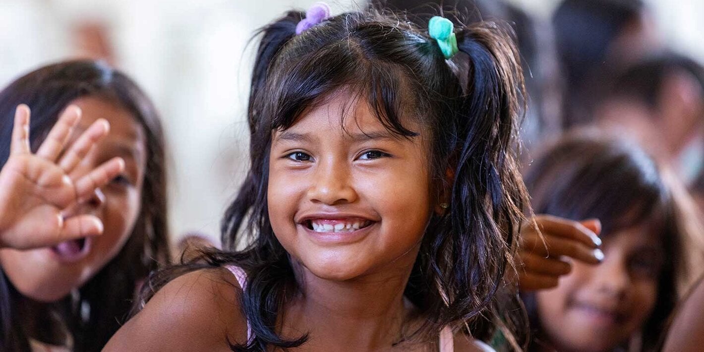 Menina sorrindo e acenando para a câmera