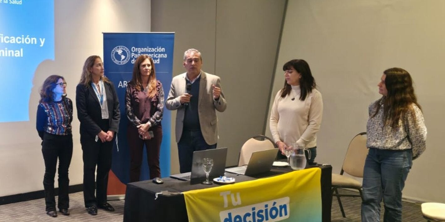 Autoridades dan inicio a la jornada. En la mesa de disertantes, una bandera dice "Tu decisión marca la diferencia"