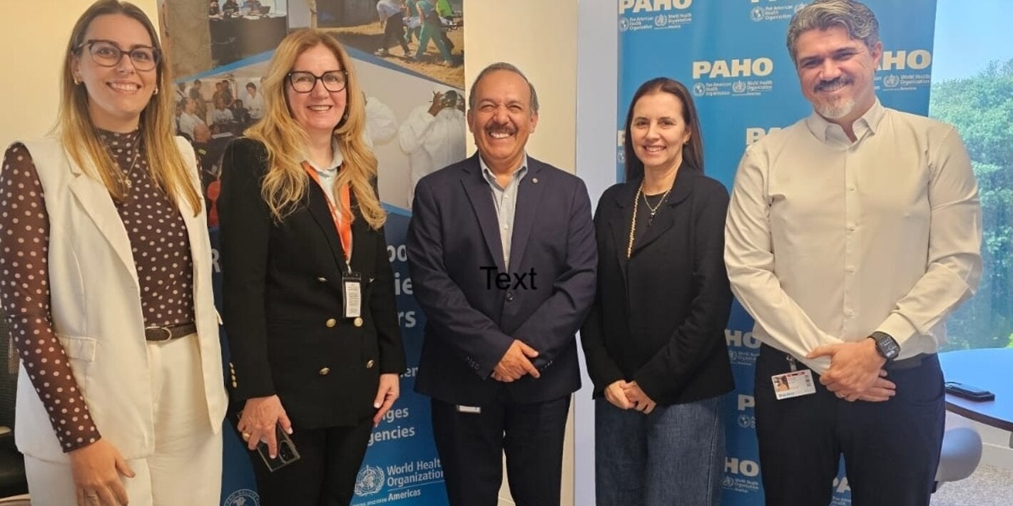 Delegación de salud de São Paulo y equipo de la OPS/OMS posan en el Centro de Operaciones de Emergencia, junto a un banner sobre respuesta a emergencias sanitarias.