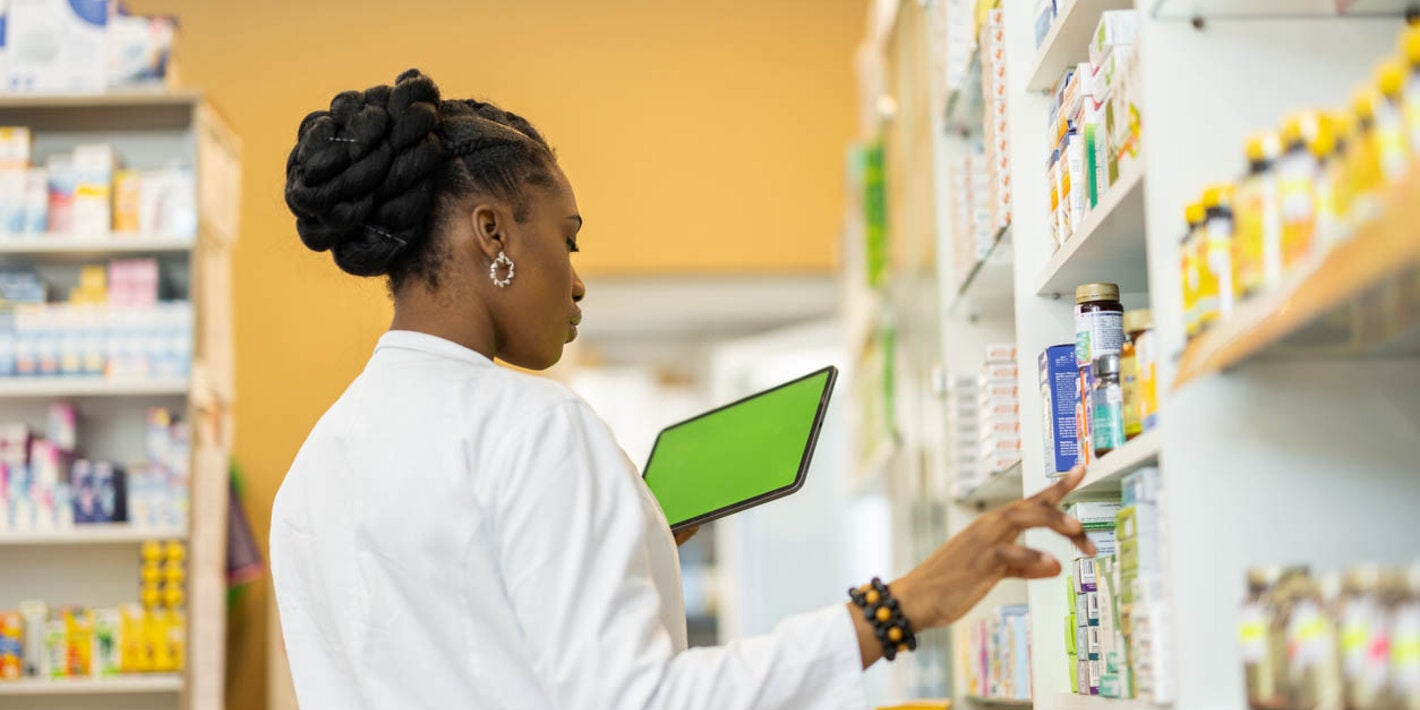 Female pharmacist checking the medicine on shelfs in drugstore